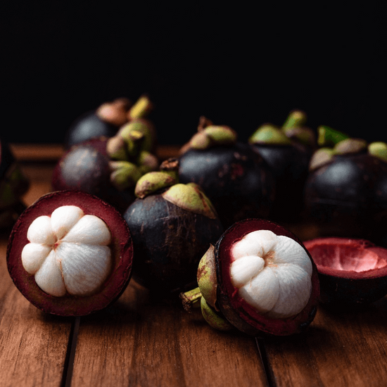 Mangosteen fruits on a wooden surface with a dark background